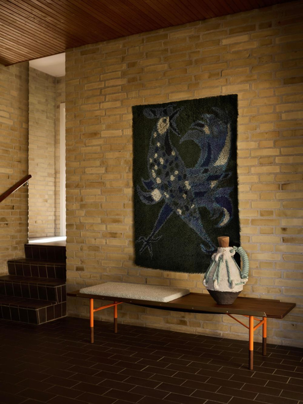 The Table Bench in walnut with orange steel legs and brass edges. Cushion with 'Safire' upholstery in the colour '0006'.