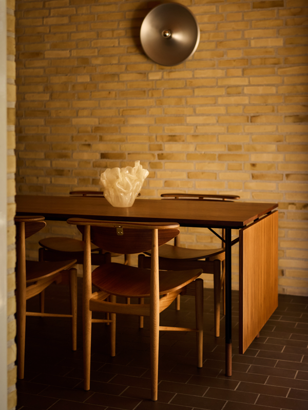 The Nyhavn Dining Table with tabletop and feet in walnut with black steel legs, paired elegantly with the Reading Chair.