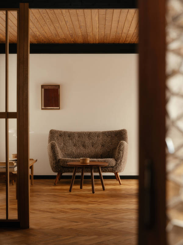 The Poet Sofa with walnut legs upholstered in sheepskin in the color 'Sahara'. 